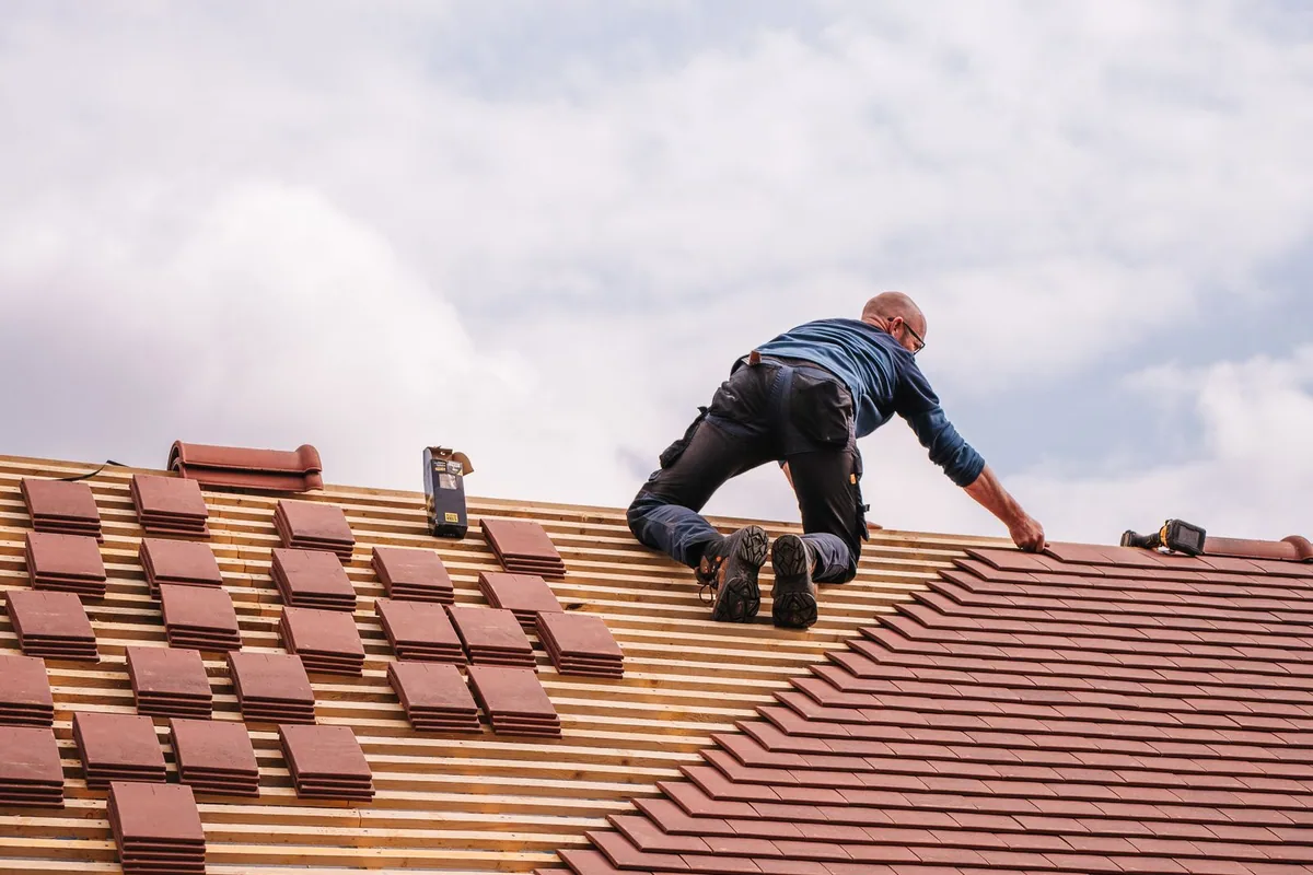 Couvreur professionnel travaillant sur une toiture en tuiles